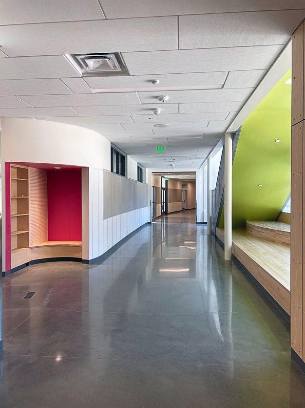 part of a hallway with wood benches on one side by the windows and a curved nook on the other side